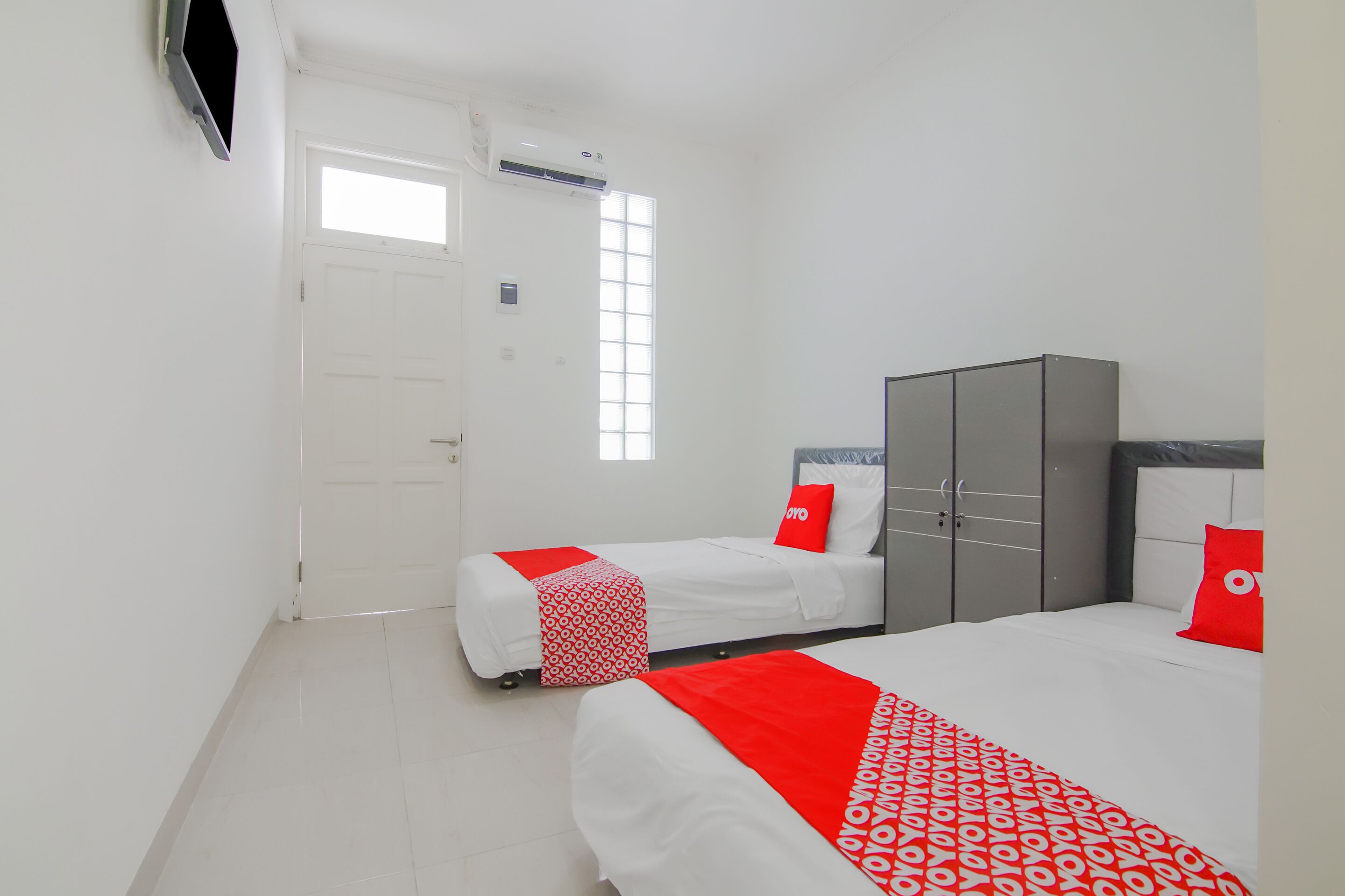 Une chambre d’hôtel avec deux lits, une armoire, une porte et une fenêtre.