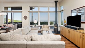 A modern living room with a large sectional sofa, a flat-screen TV, and a fireplace. - Magnificent Panoramic Valley and Vineyard Views, Single Level Two Guest Suite Layout, Amazing Deck (Dundee)