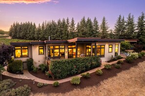 A modern two-story house with large windows, a covered patio, and a well-maintained garden. - Magnificent Panoramic Valley and Vineyard Views, Single Level Two Guest Suite Layout, Amazing Deck (Dundee)