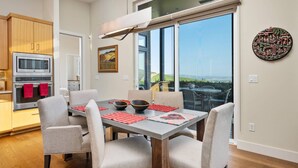A modern kitchen with stainless steel appliances, a dining area with a large table and chairs, and a scenic view through large windows. - Magnificent Panoramic Valley and Vineyard Views, Single Level Two Guest Suite Layout, Amazing Deck (Dundee)