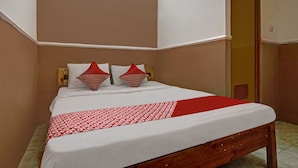 Een netjes opgemaakt bed met een rood-witte spreideken, twee kussens met een rood-wit ontwerp en een houten hoofdbord.