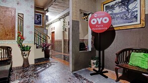 Een receptiegedeelte met een betegelde vloer, een houten bankje, een groene handdoek en een bordje met de tekst 'OYO Paris Residence'.