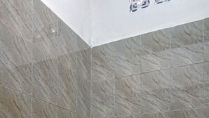 Een badkamer met toilet, douche en een marmeren wand.
