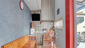 A compact room with a wooden bench, a small table, a water dispenser, and a TV mounted on the wall. - OYO 92047 Penginapan Arfi Syariah (Pekanbaru)
