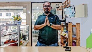 A man in a shop with a display of motorcycles and a TV on the wall. - OYO 92047 Penginapan Arfi Syariah (Pekanbaru)