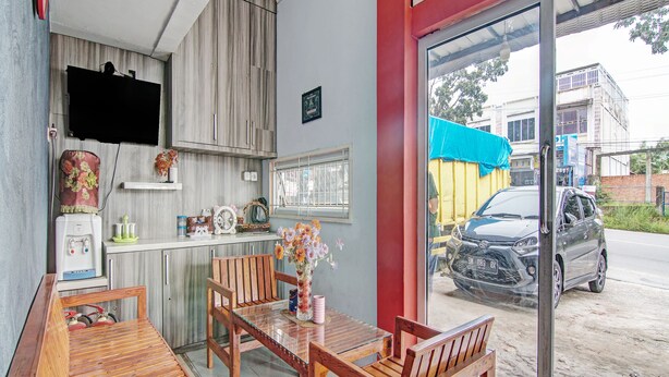 A restaurant with wooden furniture, a counter, and a view of the street. - OYO 92047 Penginapan Arfi Syariah (Pekanbaru)
