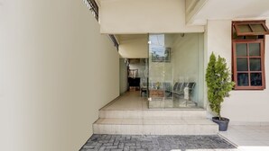 A modern entrance with a glass door, a small potted plant, and a tiled floor. - OYO 91361 Benlin D'kost Syariah (Surabaya)