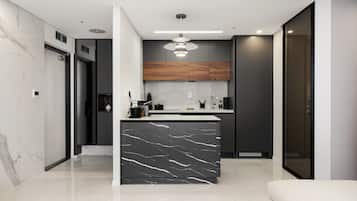 A modern kitchen with a marble island, dark cabinets, and a pendant light.