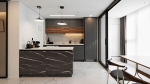 Una cocina moderna con una isla de mármol, iluminación colgante y vistas a la ciudad.