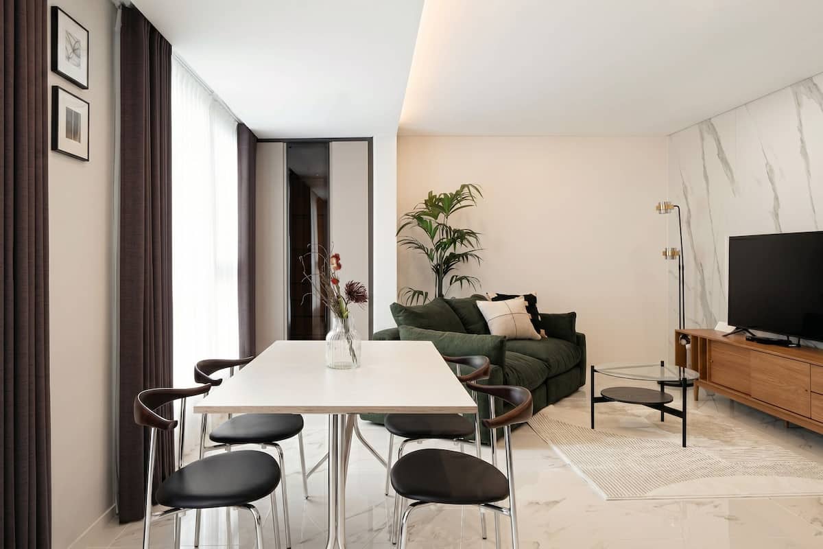 A modern living room with a dining table, chairs, a sofa, a TV, and a plant.