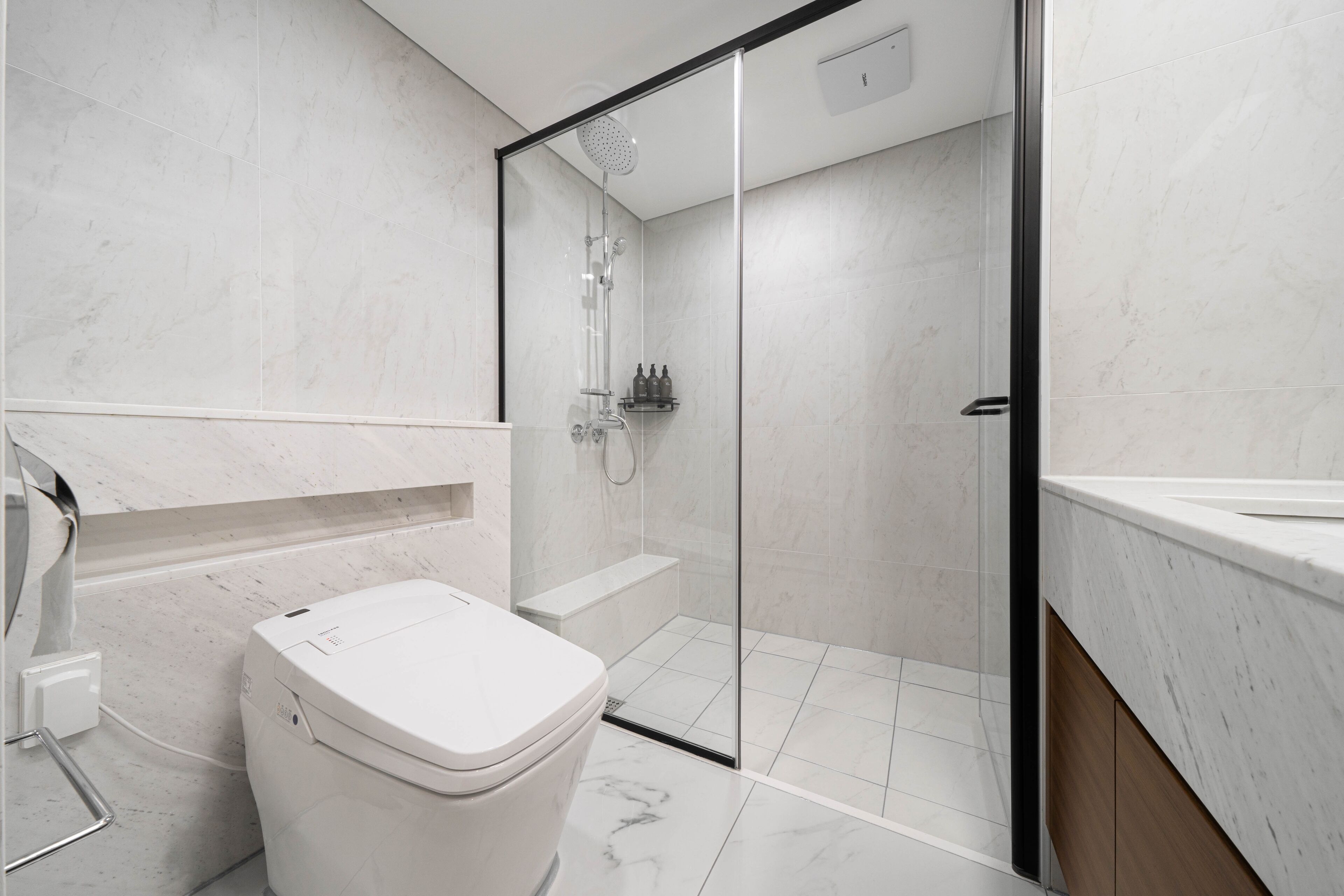 A modern bathroom with a toilet, shower, and sink.