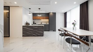 Una cocina moderna con una isla de mármol, iluminación colgante y un comedor con mesa y sillas.