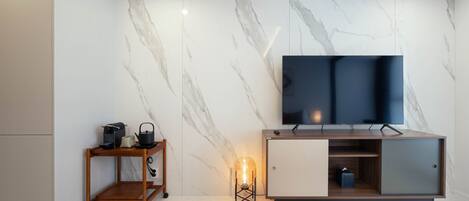 A modern living room with a marble wall, a flat-screen TV, a wooden side table, and a floor lamp.
