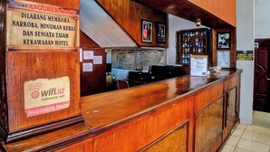 A wooden reception desk with a sign indicating the availability of wifi and a notice about the hotel. - Hotel O Serena Anggrek (Medan)