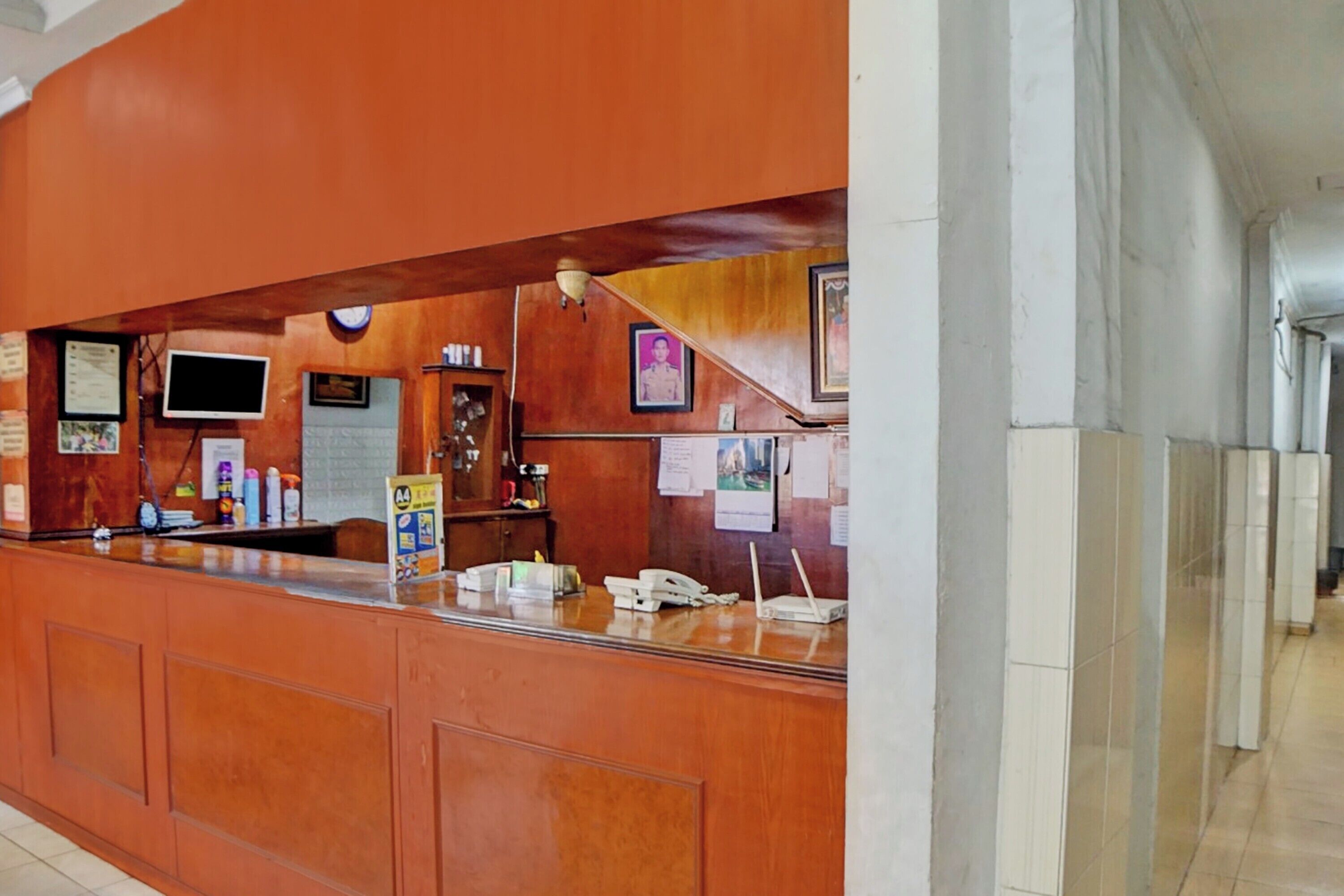 A reception area with a wooden counter, a clock, and various notices and signs.