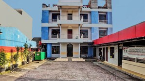 A multi-story building with a central entrance, balconies, and a red awning on the right. - Hotel O Serena Anggrek (Medan)