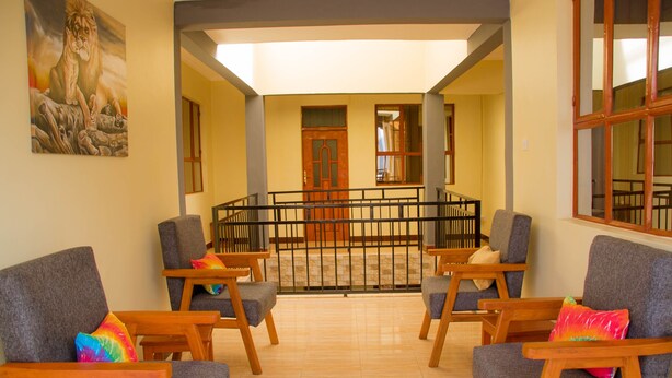 A lobby with a seating area, a staircase, and a view of the interior. - HECASA HOMESTAY (Arusha)