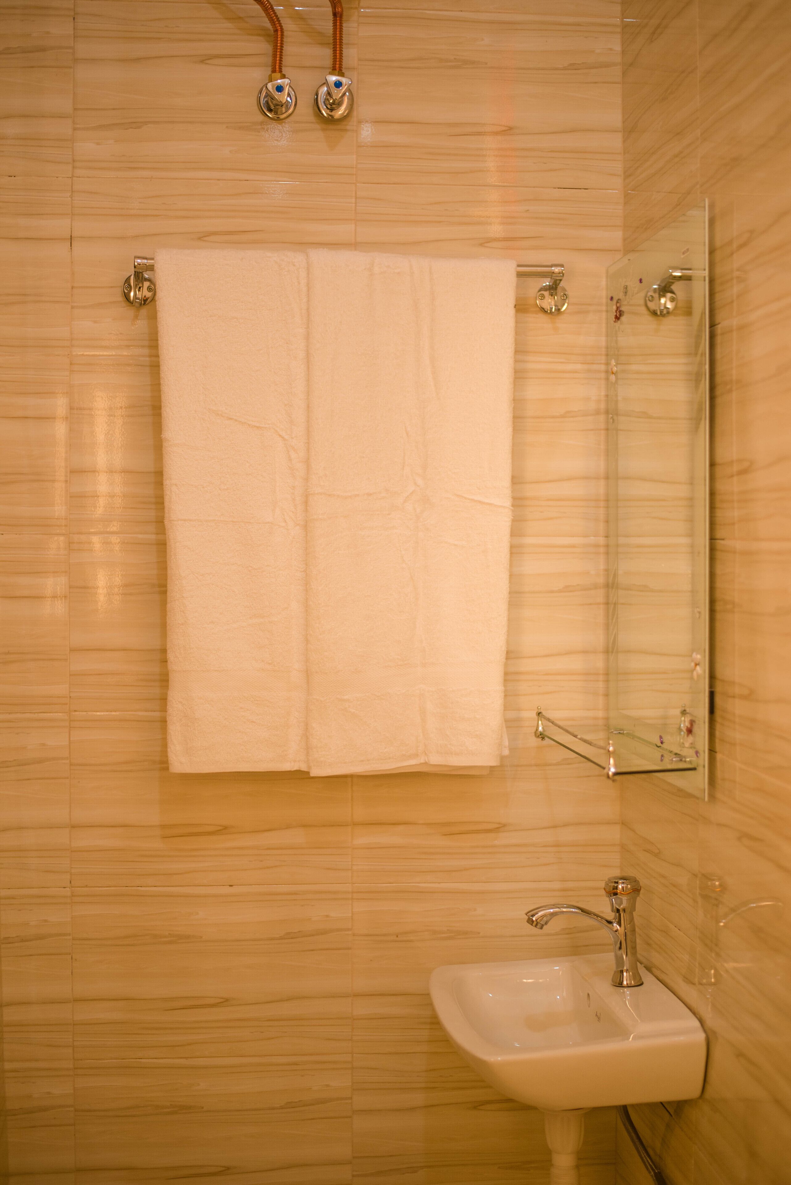 A bathroom with a white sink, a towel hanging on a towel rack, and a mirror on the wall.