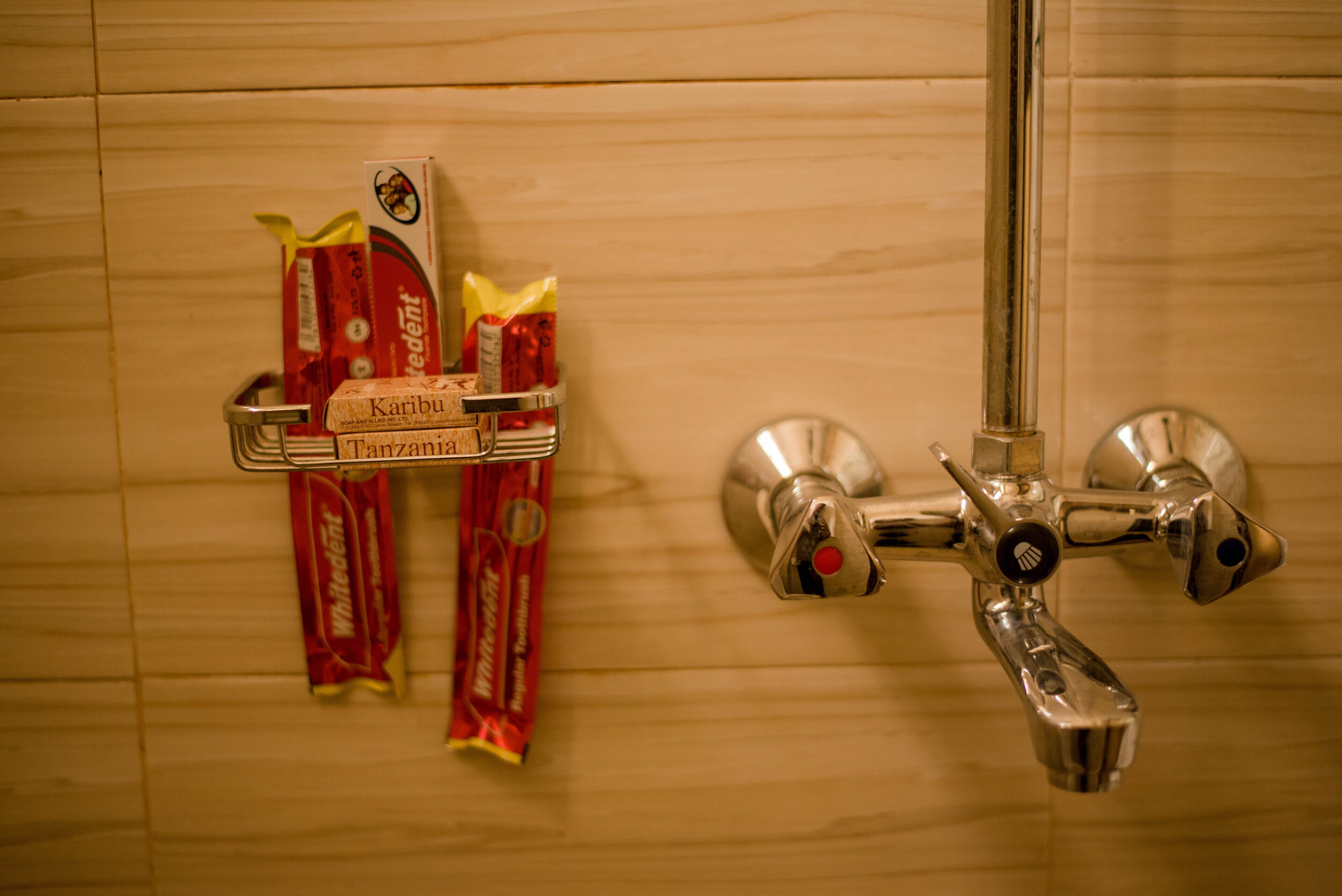 Un baño con cabezal de ducha y dispensador de jabón fijados a la pared.