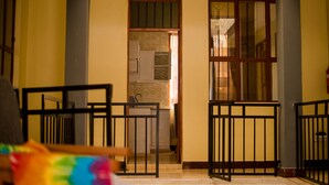 A hallway with a kitchen area, a staircase, and a gate. - HECASA HOMESTAY (Arusha)