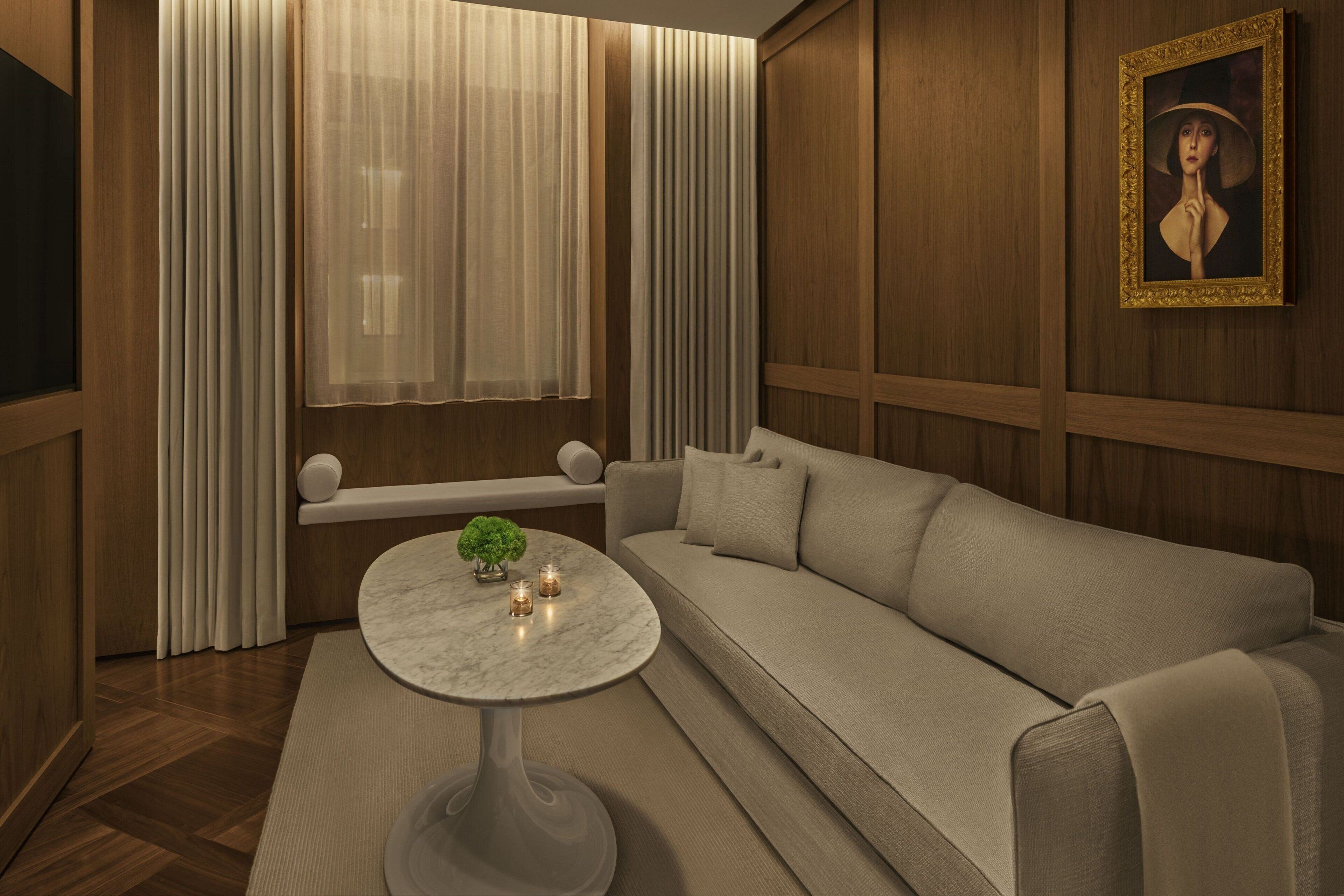 A modern living room with a marble coffee table, a beige sofa, and a painting on the wall.