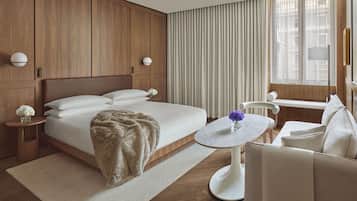 A hotel room with a large bed, a round table, a sofa, and a window with curtains.