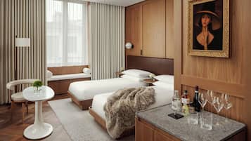 A hotel room with two beds, a sitting area, a small round table, and a bar area with glasses and bottles.
