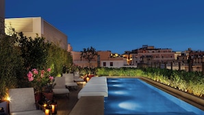 A rooftop pool area with lounge chairs, potted plants, and a view of surrounding buildings. - The Rome EDITION (Rome)
