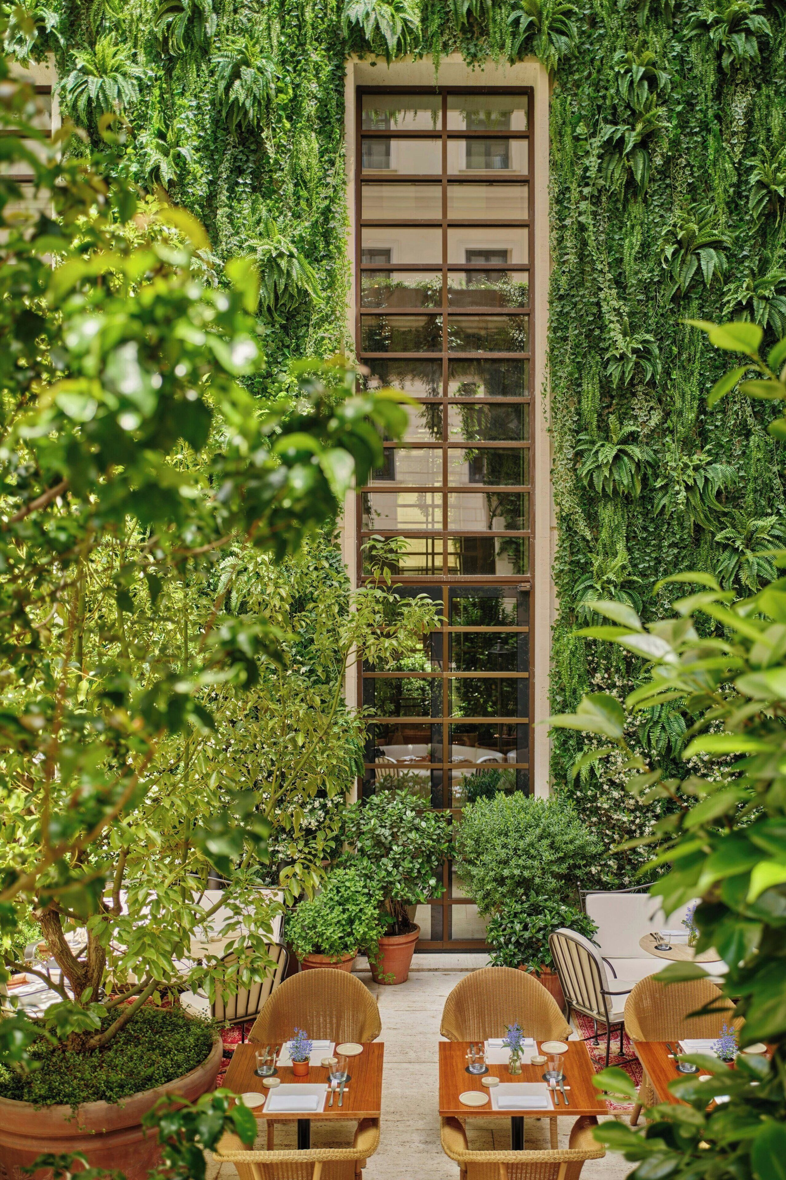 A restaurant with a vertical garden wall, outdoor seating, and potted plants.