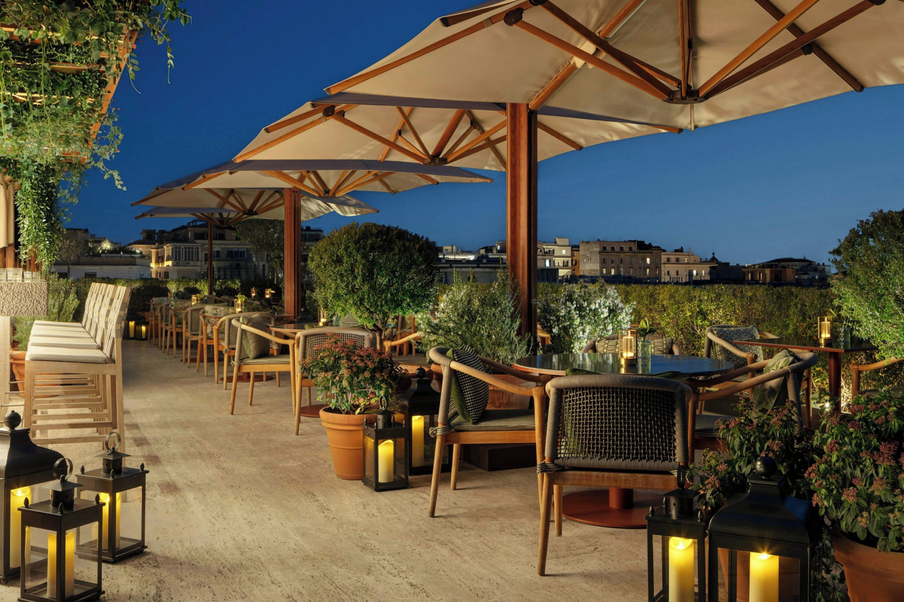 An outdoor seating area with wooden furniture, umbrellas, and lanterns.