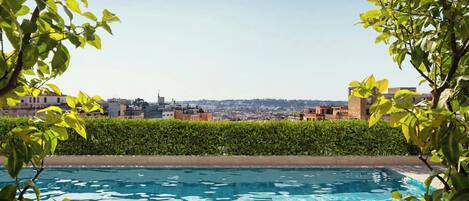A swimming pool with a city view, surrounded by greenery.