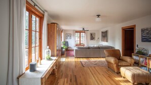 A spacious living room with wooden flooring, a sofa, a leather armchair, and a bookshelf. - The Gorge Onsen Spa (Washougal)