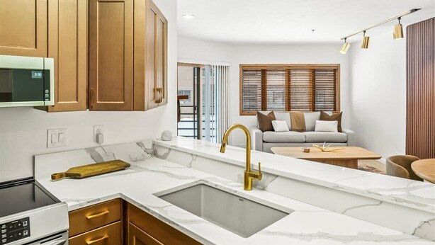 A modern kitchen with a white countertop, gold cabinets, and a built-in oven. - Luxe DV Condo at Snow Park (Park City)
