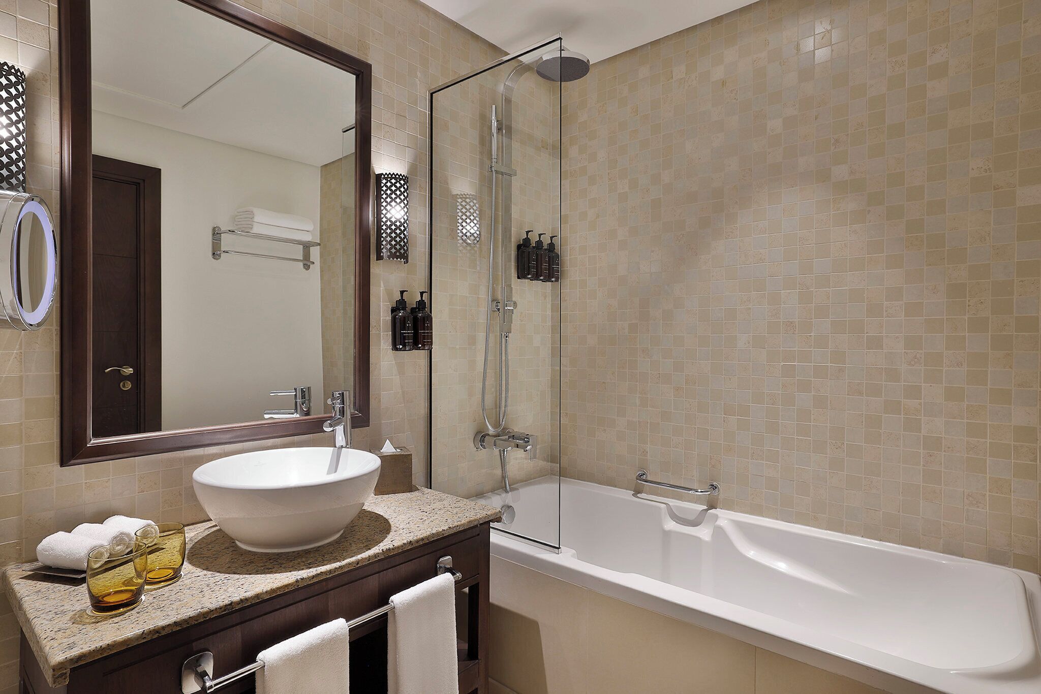 A bathroom with a large mirror, a sink, a bathtub, and a glass-enclosed shower.