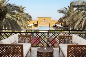A balcony with a pool view, white sofas, and a decorative fence. - Aldhafra Resort, Vignette Collection by IHG (Madinat Zayed)