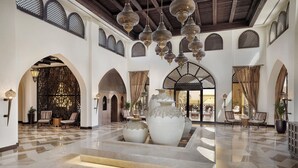 A spacious lobby with high ceilings, ornate chandeliers, and a central seating area with large vases. - Aldhafra Resort, Vignette Collection by IHG (Madinat Zayed)