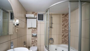 A bathroom with a sink, toilet, shower, and a glass-enclosed shower stall. - HALLEY OTEL (Denizli)