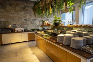 Uma cozinha moderna com uma parede de pedra, um balcão de buffet com pratos e utensílios, e plantas penduradas.
