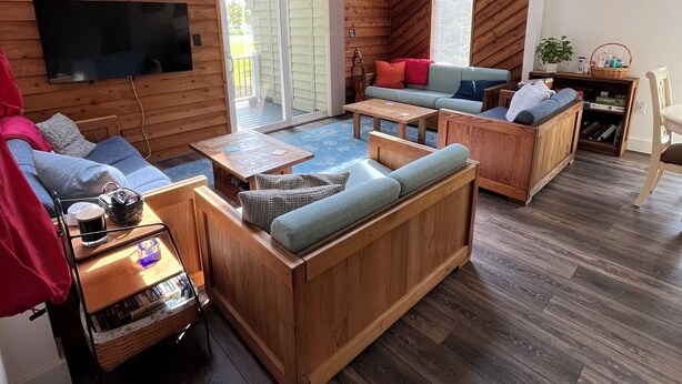 Una habitación acogedora de estilo cabaña, con paredes de madera, un ventanal grande y un televisor de pantalla plana montado en la pared.