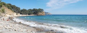 A beach with rocky terrain, clear skies, and a distant cliff with trees. - Duplex with an ocean view (La Ciotat)