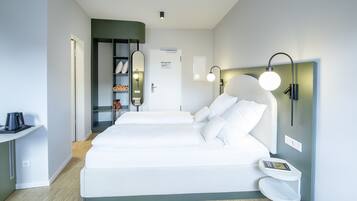 Una habitación de hotel moderna con una cama grande, mesitas de noche, un armario y una pequeña zona de estar.