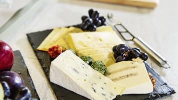 Una selección de quesos y frutas sobre una tabla de pizarra.