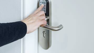 A hand using a numeric keypad on a modern door lock.