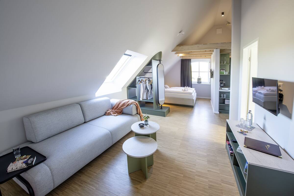 Una habitación moderna estilo loft con cama elevadas, un sofá, una mesa de comedor y un televisor.