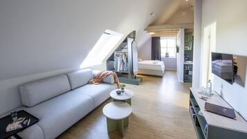 Een moderne loftkamer met een entresolbed, een bank, een eettafel en een televisie.