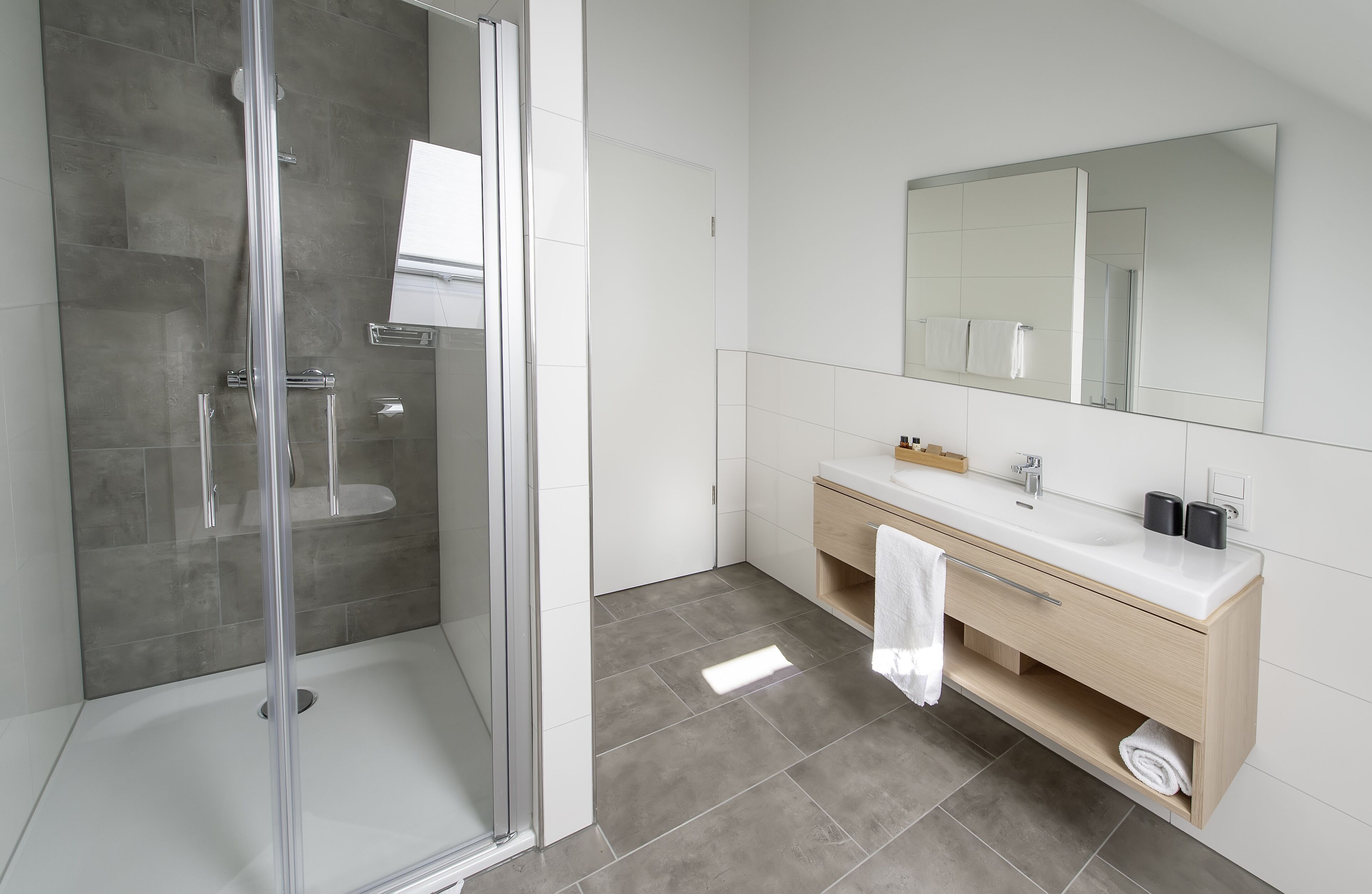 Une salle de bain moderne avec une douche à parois de verre, un lavabo blanc et un grand miroir.
