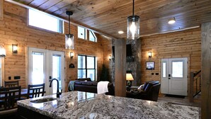 Una cocina amplia con encimeras de granito, paredes de madera e iluminación colgante.