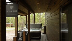 Una terraza de madera con un jacuzzi y un cartel que dice "Welcome to Baby Bear Bungalow".