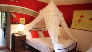 Une chambre à coucher avec un lit à baldaquin, une table de chevet, une lampe et un tableau au mur.