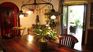 Une table à manger en bois, agrémentée d’un vase à rayures contenant des fleurs, d’un lustre et offrant une vue sur l’extérieur.